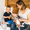 A mother is sitting on stairs with her two children, holding a baby and a stuffed animal. Náhľad obrázku produktu