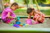 Two young girls playing in a sandbox with toys. Podgląd zdjęcia produktu