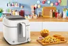 A kitchen counter with a deep fryer and fried food. Produktbild-Vorschau