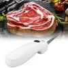 Weißes elektrisches Tranchiermesser mit Wellenschliffklinge, vor einem rohen Steak mit Kräutern und Gemüse Anteprima dell’immagine prodotto