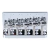 A close-up, straight-on view of a chrome-plated 5-string bass guitar bridge against a white background. Podgląd zdjęcia produktu