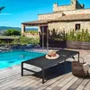 A sun lounger with a hat and a basket on a wooden deck next to a swimming pool, with a stone house in the background. Voir les images du produit