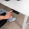 A person's hand is pressing buttons on a control panel attached to a white desk. Produktbild-Vorschau