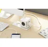 A white power cube with multiple outlets and USB ports is shown on a wooden desk next to a keyboard and a smartphone charging. Anteprima dell’immagine prodotto