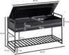 A black storage bench with a lift-top lid and a slatted shelf underneath, shown with dimensions indicated by dashed lines and measurement labels. Produktbild-Vorschau