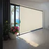 A large beige roller blind is installed on a sliding glass door overlooking a swimming pool and the ocean. Náhled obrázku produktu