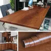 A collage of images showing a wooden desk, a kitchen interior, and a roll of wood-grain contact paper. Produktbild-Vorschau