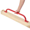 A hand holding a red climbing handle attached to a wooden beam. Náhľad obrázku produktu