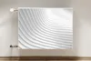 A white radiator cover with a wave-like pattern is mounted on a light gray wall. Produktbild-Vorschau