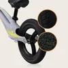 Close-up view of a balance bike's rear wheel and frame, with magnified insets showing the tire tread and grip material. Produktbild-Vorschau