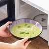 Eine gefüllte Schale wird vor die geöffnete Mikrowelle gehalten. Voir les images du produit