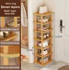 A tall, narrow wooden shoe rack with seven shelves, filled with shoes and a handbag, placed in a corner next to a door and a closet. Produktbild-Vorschau