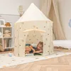 A young girl is reading a book inside a beige play tent decorated with stars and hearts. Náhled obrázku produktu