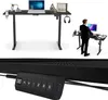 A black electric standing desk with a laptop, headphones, and decorative items on it, and a man in a suit using a similar desk in the background.
