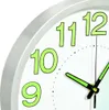 A close-up of a white wall clock with green numbers and hands. Voir les images du produit