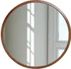 A round mirror with a wooden frame is shown against a light-colored wall with window light reflections. Anteprima dell’immagine prodotto