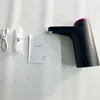 A black water bottle pump with a pink top, a USB charging cable, a clear tube, and a user manual are laid out on a white surface. Náhled obrázku produktu
