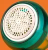 Close-up of the top of a fabric shaver with a perforated metal surface and a green plastic casing. Náhled obrázku produktu