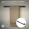 A black towel holder mounted on a wall with a beige towel draped over it. A close-up inset shows the towel holder's design and dimensions. Produktbild-Vorschau