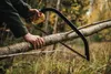 A person is using a bow saw to cut a tree branch in a forest. Náhled obrázku produktu