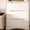A white three-drawer dresser is shown in a room with a beige upholstered ottoman to the left. Podgląd zdjęcia produktu