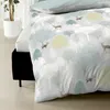 A close-up view of a duvet cover with a forest and deer pattern, laid on a bed. Produktbild-Vorschau