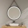 A round LED mirror hangs above a sink in a bathroom. Anteprima dell’immagine prodotto