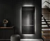 A modern interior with a large, illuminated mirror reflecting a dimly lit room, a console table with a sculpture, and a staircase. Produktbild-Vorschau