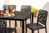 An outdoor dining set with black chairs and a black table, set on a patio with potted plants in the background. Anteprima dell’immagine prodotto