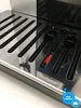 A close-up view of the drip tray and accessories of a coffee machine. Produktbild-Vorschau