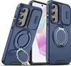 Two blue phone cases with a ring stand and camera cover are displayed diagonally against a white background. One case is in the foreground, angled towards the viewer, while the other is slightly behind and to the right, showing a different perspective. Náhled obrázku produktu