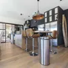 A modern kitchen with a breakfast bar and bar stools, featuring a stainless steel trash can. Anteprima dell’immagine prodotto