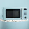 A light blue retro-style microwave oven is placed on a light blue surface, surrounded by popcorn. Podgląd zdjęcia produktu