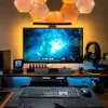 A modern gaming or computer setup with a large monitor, keyboard, mouse, headphones, and ambient lighting. Produktbild-Vorschau