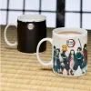 Two Demon Slayer themed mugs are displayed on a woven mat. Produktbild-Vorschau
