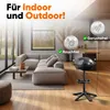 A modern living room with a sectional sofa and a grill on a stand, with kitchen elements in the background. Produktbild-Vorschau