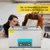 A woman leans on her hand, looking at an ultrasonic cleaner, while a man in overalls works in the background. Anteprima dell’immagine prodotto