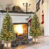Two decorated Christmas trees flank a fireplace with a fire burning. Christmas stockings hang on the wall. Podgląd zdjęcia produktu