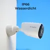 A white security camera with water droplets on it, mounted on a white wall, with a bright blue sky in the background. Produktbild-Vorschau