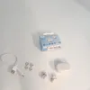 A white background with a box of white in-ear headphones, a charging cable, extra ear tips, and the charging case with earbuds. Produktbild-Vorschau