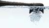A close-up shot of a black toothbrush head submerged in water, creating bubbles. Podgląd zdjęcia produktu