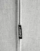 A close-up of a fabric seam with a brand tag attached. Náhled obrázku produktu