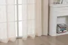A close-up view of beige linen-look curtains hanging in front of a window, with a white fireplace and a stack of books to the right. Produktbild-Vorschau
