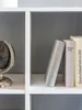 A close-up view of a white bookshelf with a globe and three books on one shelf. Produktbild-Vorschau