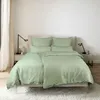 A neatly made bed with green bedding in a bedroom setting. Produktbild-Vorschau