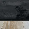 A close-up view of a black, high-pile rug on a light wooden floor. Produktbild-Vorschau