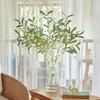A decorative LED olive branch light string in a vase on a wooden table, with a cup of tea and a book. Produktbild-Vorschau