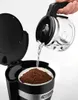 A hand is pouring water from a coffee pot into a coffee maker that contains coffee grounds. Anteprima dell’immagine prodotto
