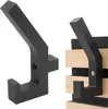 Two black coat hooks are shown against a white background. The hook on the left is shown in isolation, while the hook on the right is mounted on wooden slats with dark felt backing. Produktbild-Vorschau