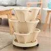 A multi-tiered planter with wheels, shown indoors on a rug. Voir les images du produit